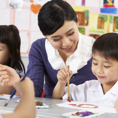 18709629 - teacher helping students during art class in chinese school classroom